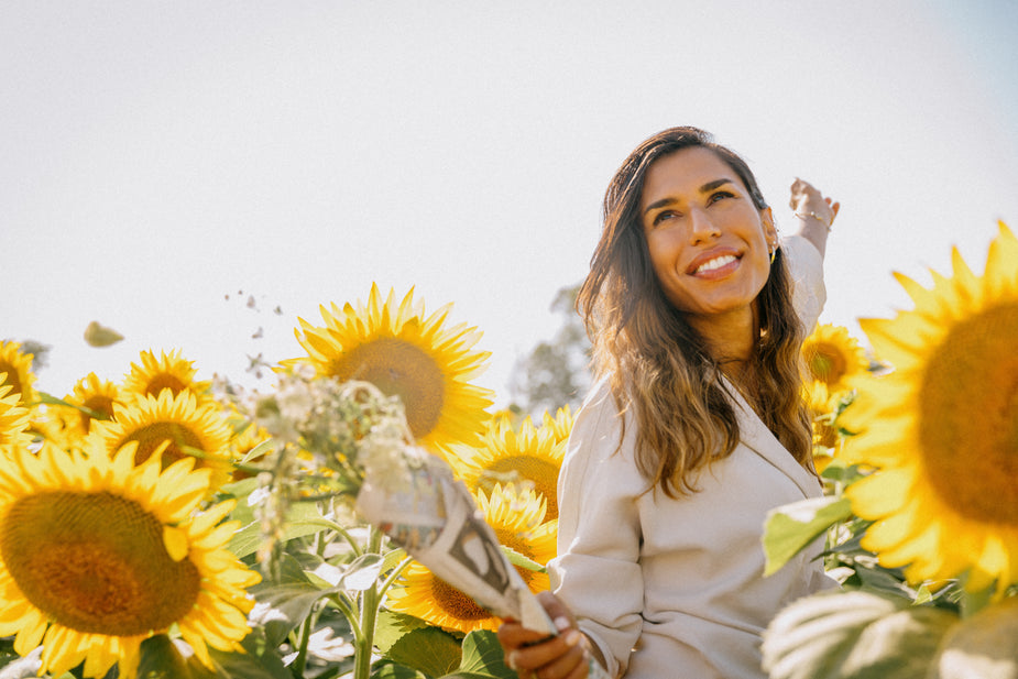 woman-in-white-jacket-smiles-surrounded-by-sunflowers
