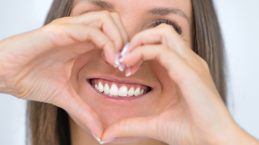 woman holding hands up as heart in front of smile