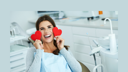 lady sitting in dental chair smiling holding hearts by her smile