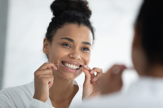 woman smiling in mirror flossing